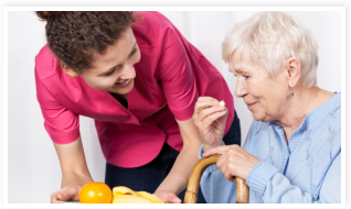 caregiver assisting her patient in taking up medicine